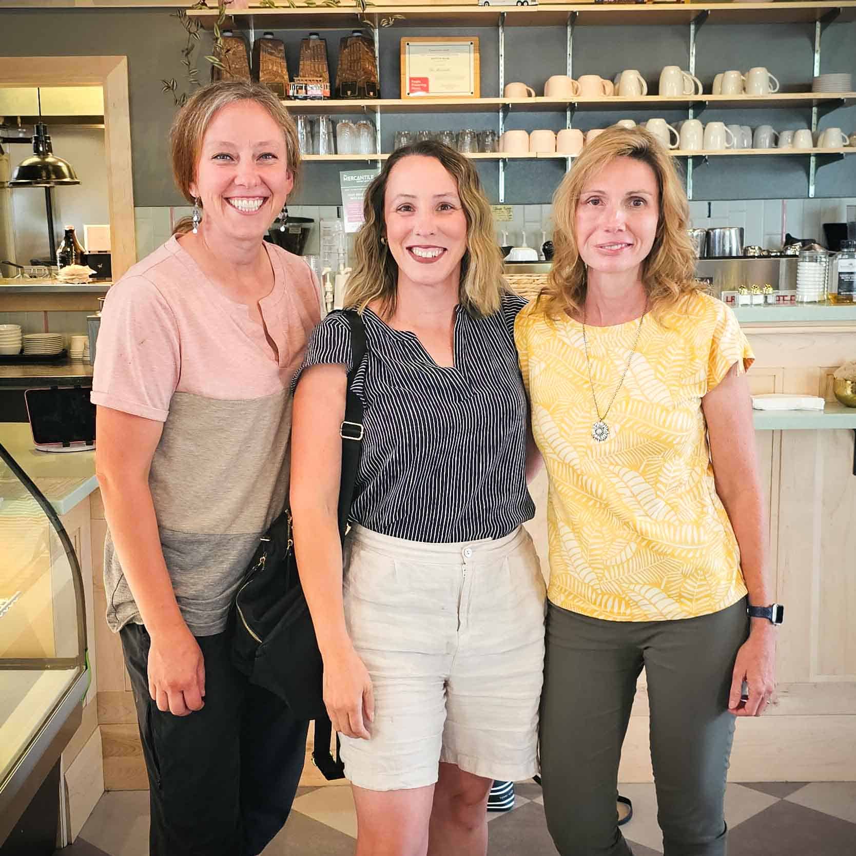 three women standing in a cafe