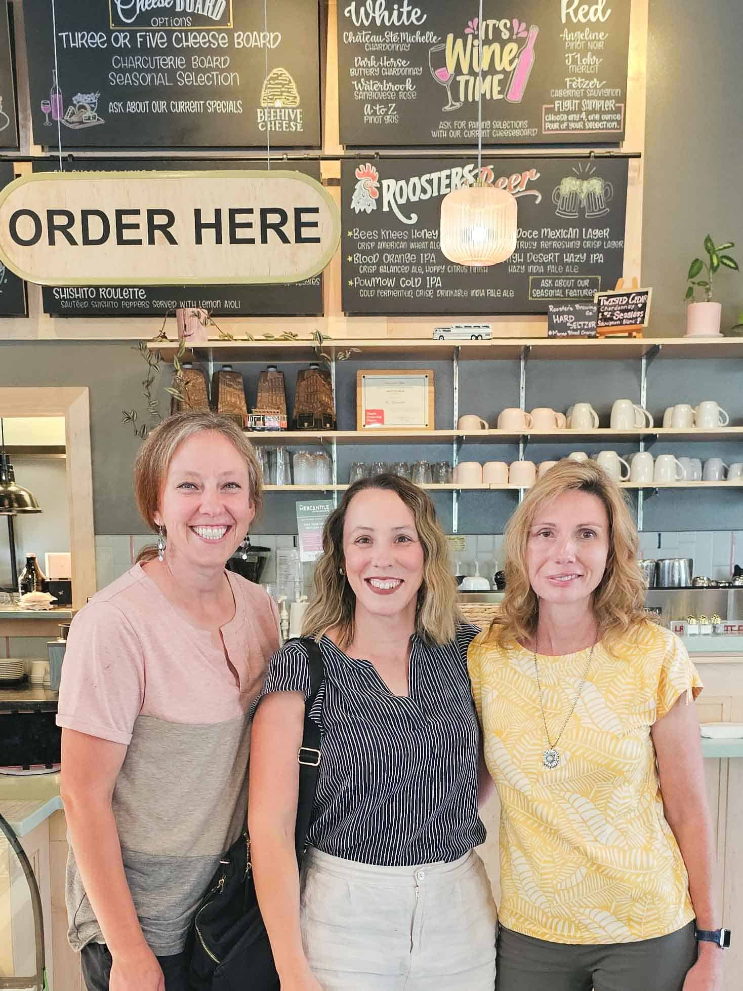 3 women standing in a cafe