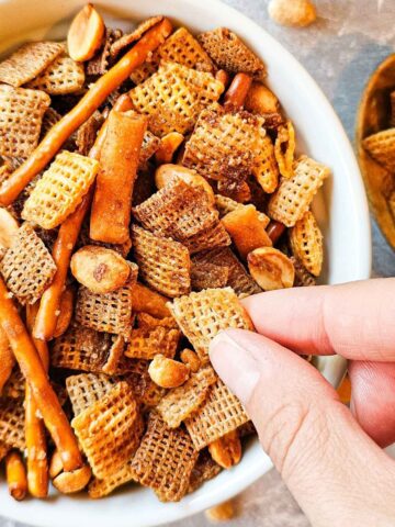 hand reaching into a bowl of snack mix