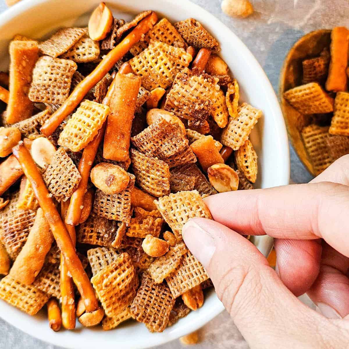 hand reaching into a bowl of snack mix