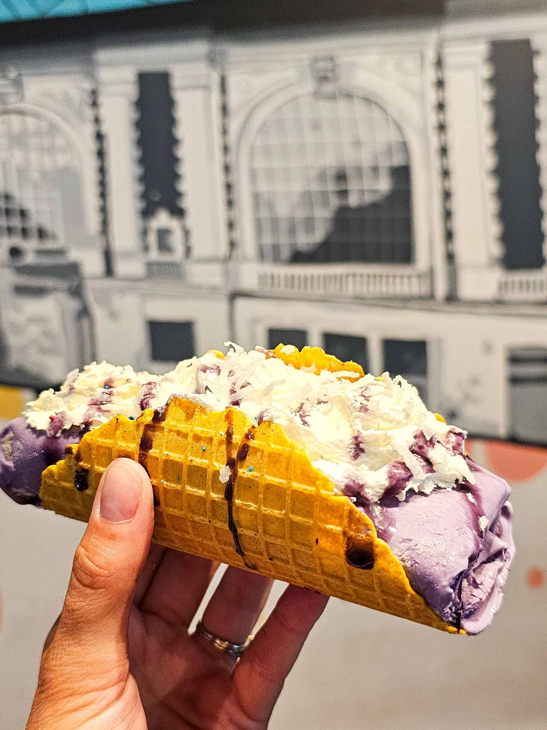 hand holding purple rolled ice cream in a taco shell