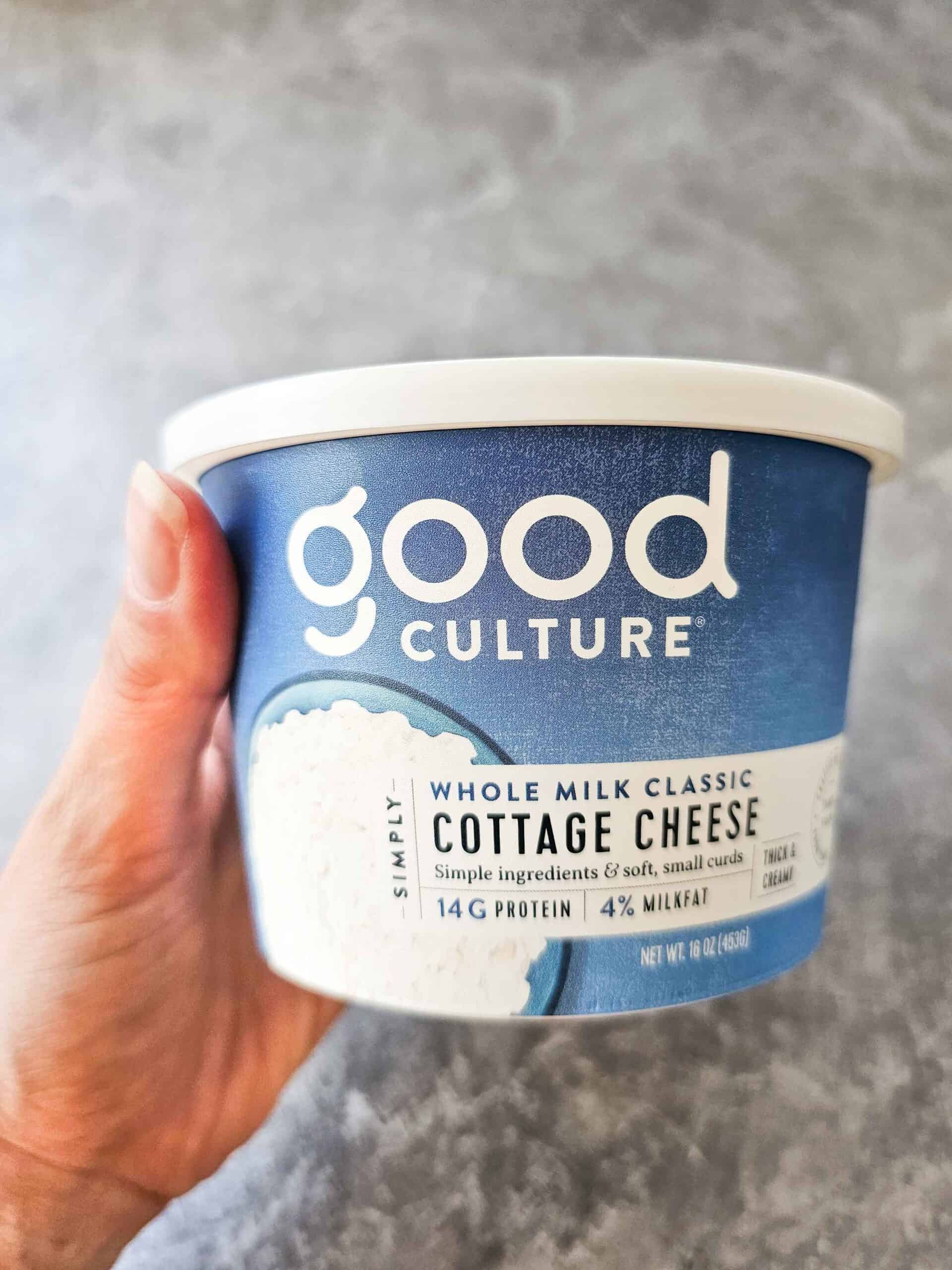 hand holding a container of cottage cheese