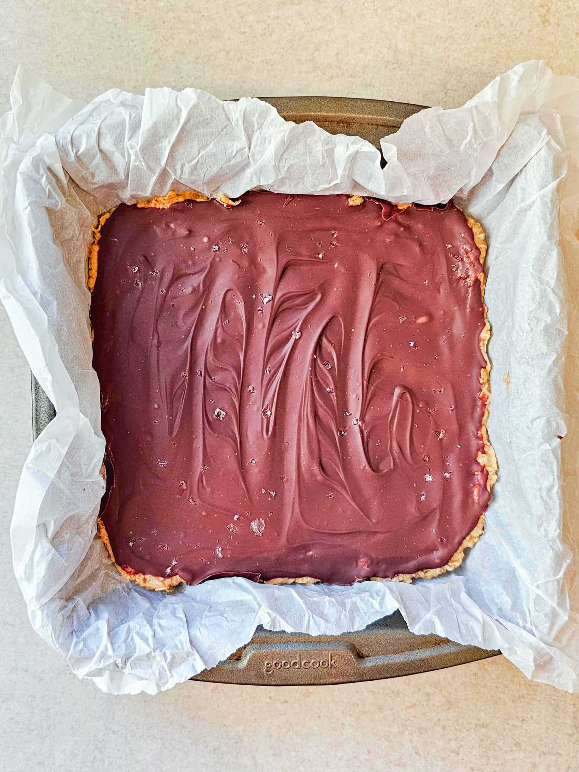 chocolate covered oat bars in a parchment lined pan