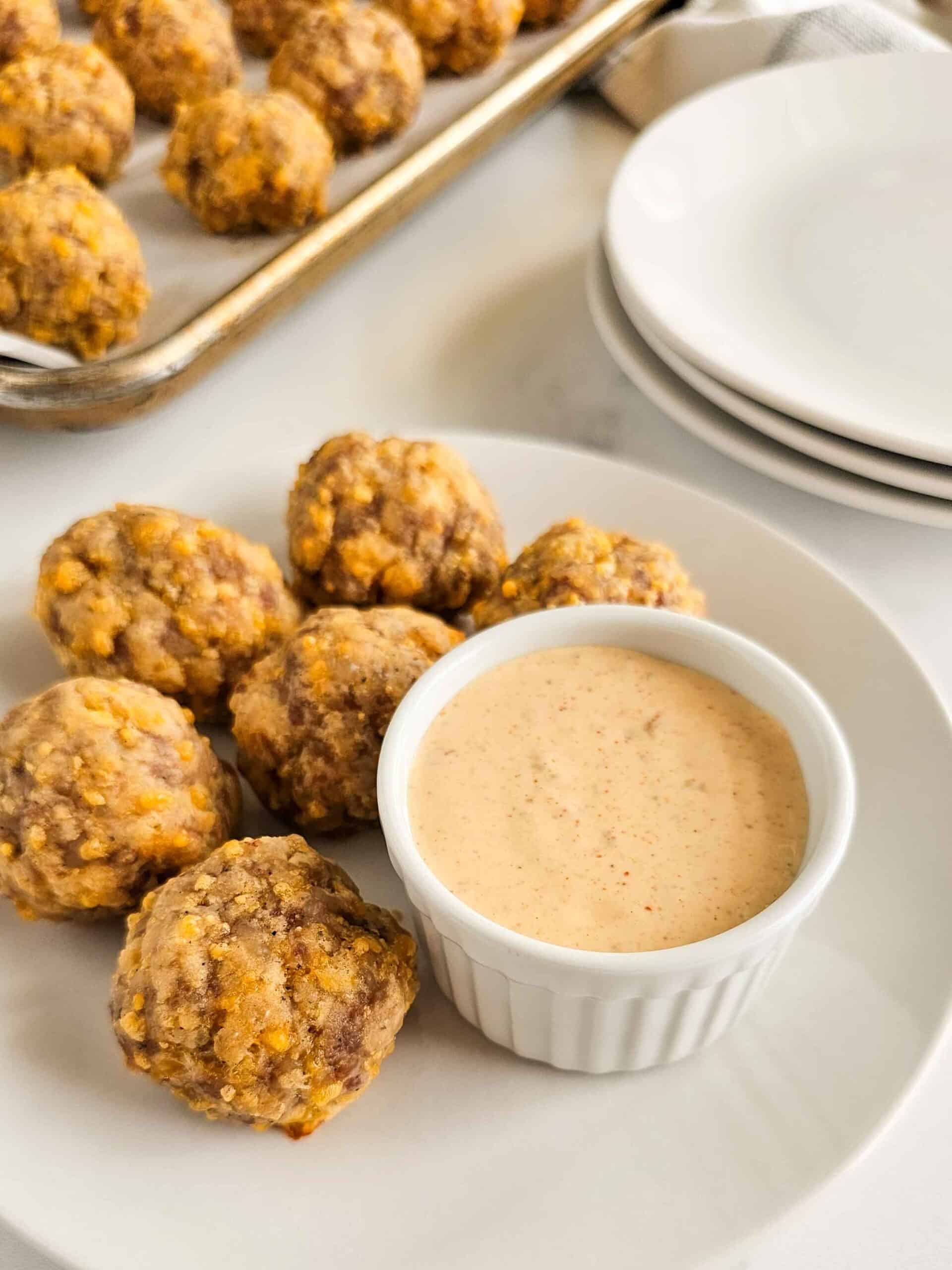 sausage balls on a plate with a bowl of sauce