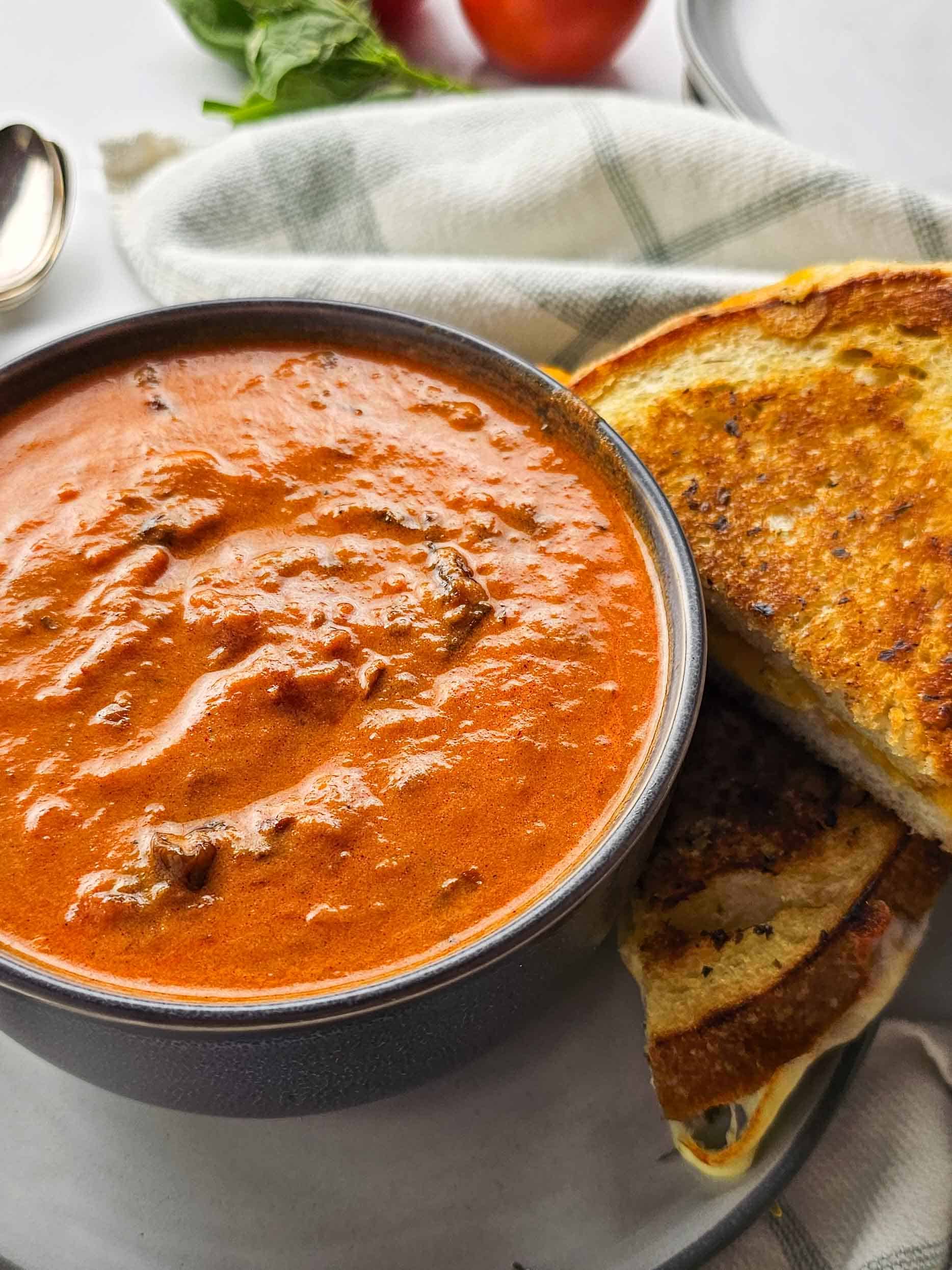 bowl of tomato soup beside grilled cheese
