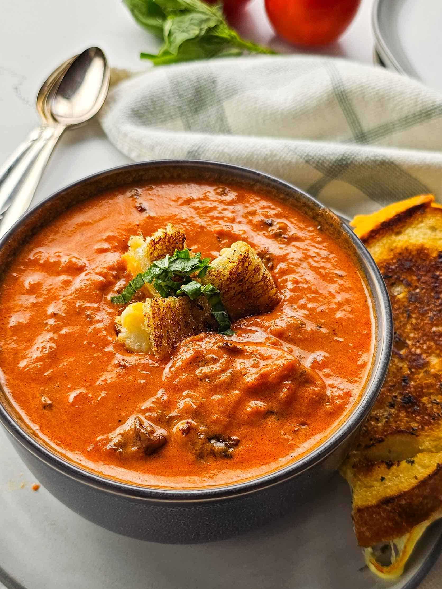 bowl of chunky tomato soup with cubes of grilled cheese